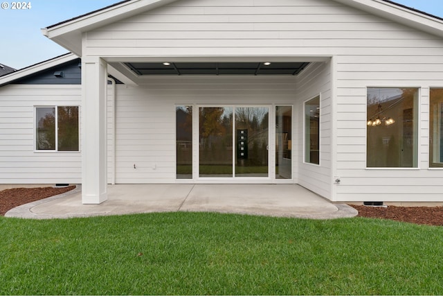 back of house with a lawn and a patio