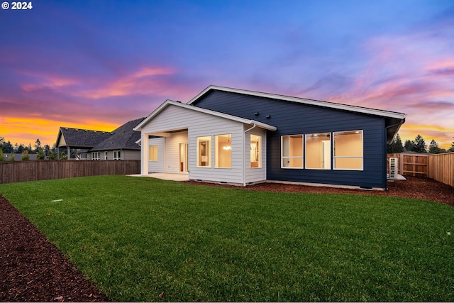 back house at dusk featuring a yard