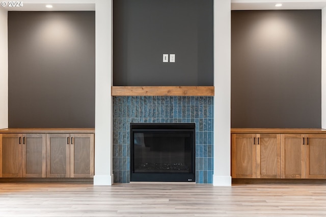 details featuring a tiled fireplace and hardwood / wood-style floors