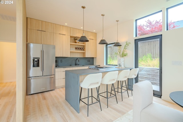 kitchen featuring decorative light fixtures, stainless steel appliances, and light brown cabinetry