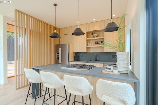 kitchen featuring hanging light fixtures, stainless steel appliances, light brown cabinets, and sink