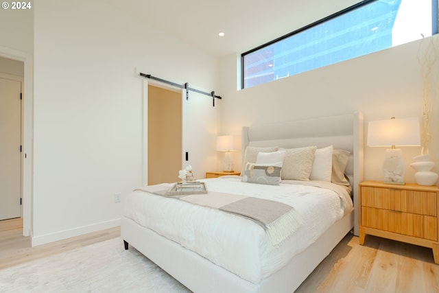 bedroom featuring a barn door and light wood-type flooring