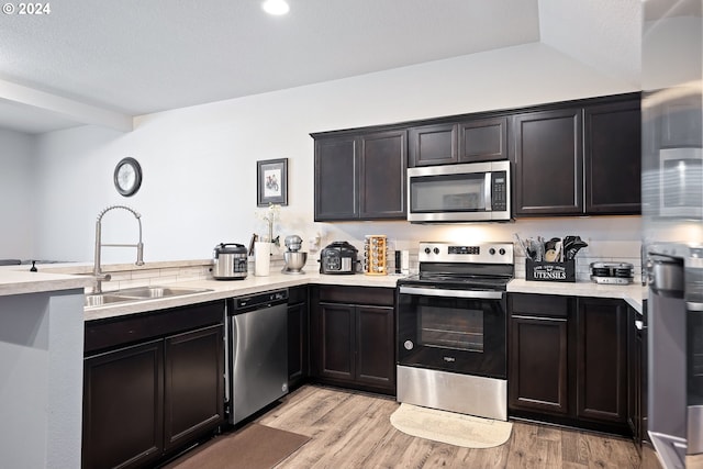 kitchen with light hardwood / wood-style flooring, stainless steel appliances, dark brown cabinets, and sink