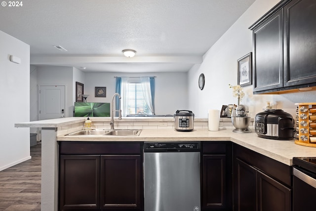 kitchen featuring sink, a textured ceiling, dark hardwood / wood-style flooring, kitchen peninsula, and stainless steel appliances