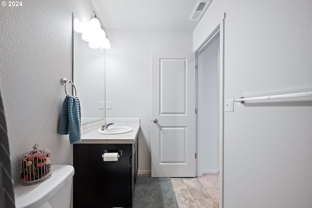 bathroom featuring toilet, a textured ceiling, and vanity