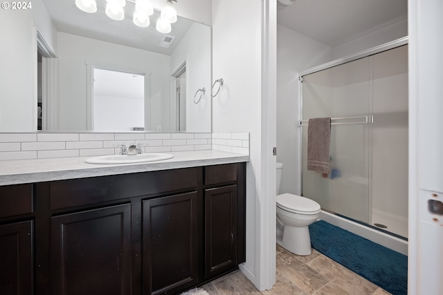 bathroom featuring a shower with door, vanity, decorative backsplash, and toilet