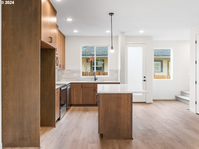 kitchen featuring a center island, sink, light hardwood / wood-style flooring, appliances with stainless steel finishes, and decorative light fixtures