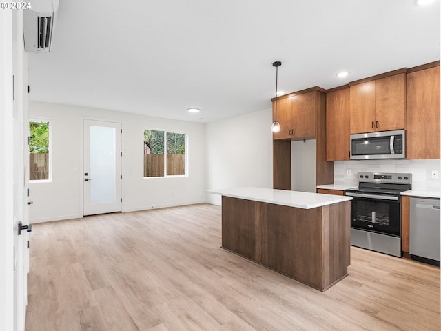 kitchen with plenty of natural light, stainless steel appliances, decorative light fixtures, and light wood-type flooring