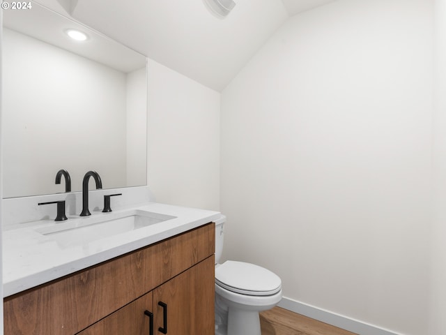 bathroom with hardwood / wood-style flooring, vanity, toilet, and vaulted ceiling