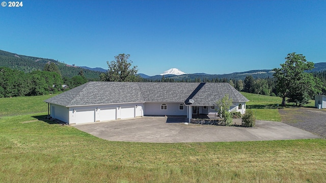 view of side of property featuring a lawn, a mountain view, and a garage