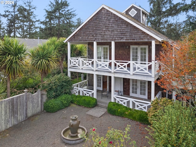 view of front facade featuring a patio, a balcony, and french doors