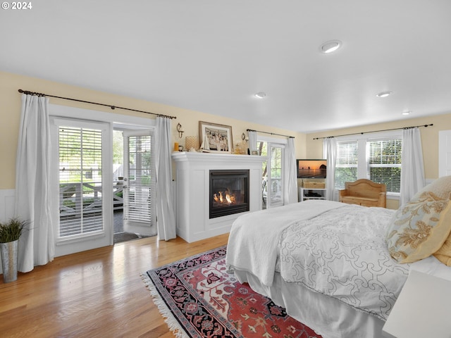 bedroom with light hardwood / wood-style floors, access to exterior, and multiple windows