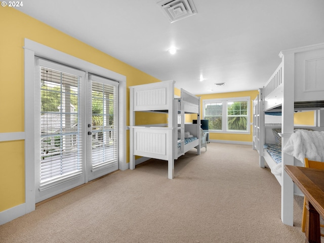 bedroom with light carpet, multiple windows, french doors, and access to outside