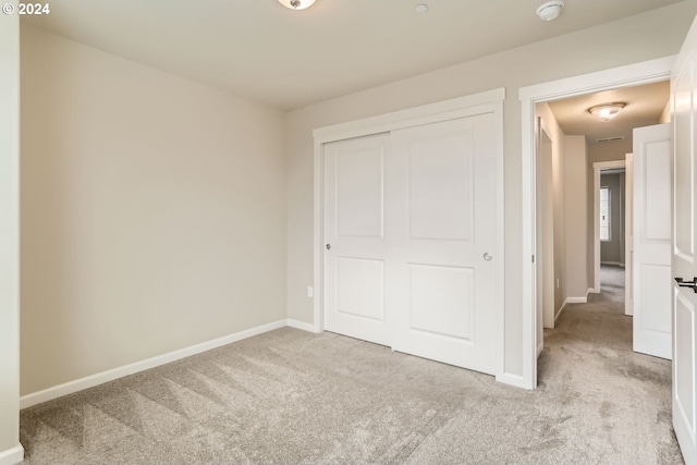 unfurnished bedroom with light carpet and a closet