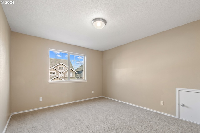 carpeted empty room featuring a textured ceiling