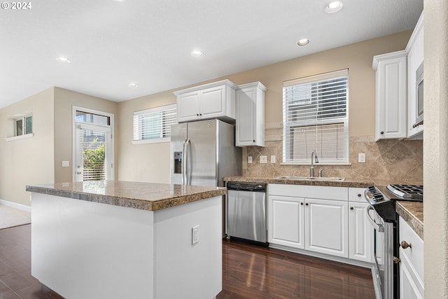 kitchen featuring stainless steel appliances, a kitchen island, white cabinetry, and sink