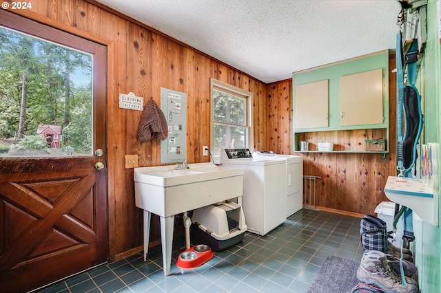 laundry area featuring a textured ceiling, washer and dryer, cabinets, wood walls, and dark tile patterned flooring