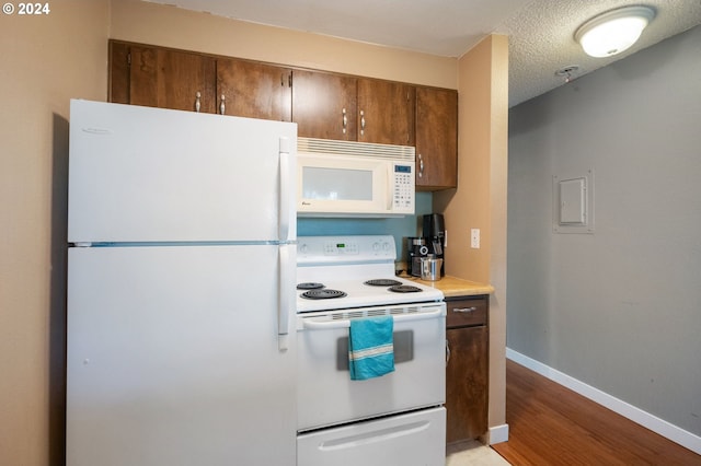 kitchen with white appliances, a textured ceiling, and light hardwood / wood-style flooring