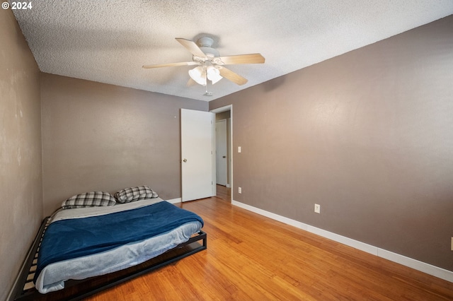 bedroom with hardwood / wood-style floors, a textured ceiling, and ceiling fan