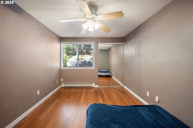 empty room featuring ceiling fan, a textured ceiling, baseboard heating, and hardwood / wood-style floors