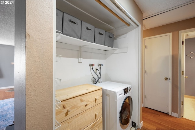 clothes washing area with a textured ceiling, washer / clothes dryer, and wood-type flooring