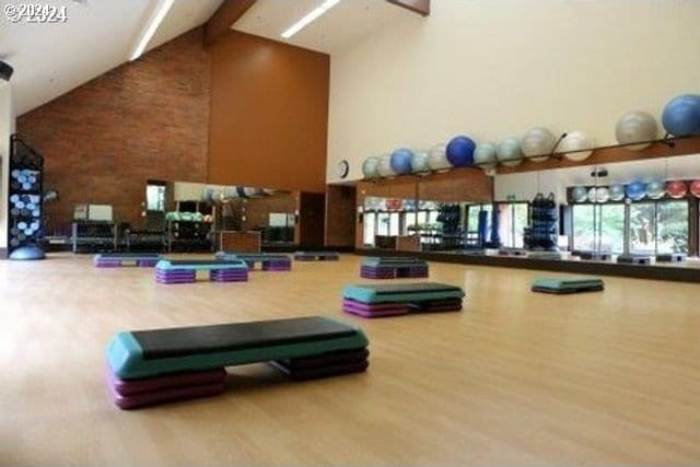 gym featuring hardwood / wood-style floors and high vaulted ceiling