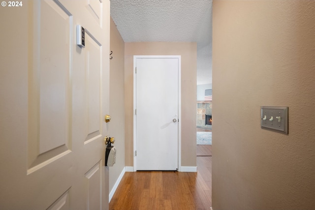 hall with a textured ceiling and light wood-type flooring