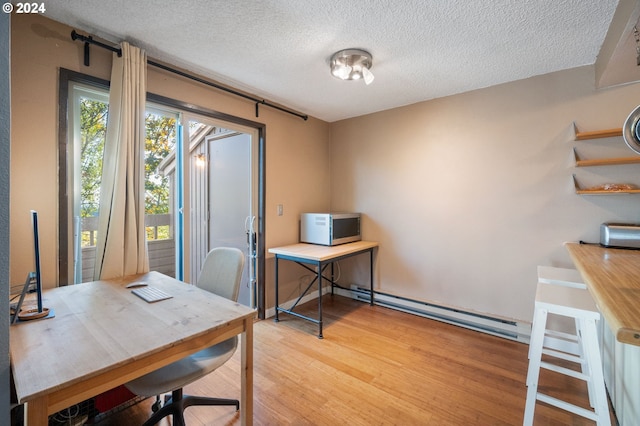 office space featuring a baseboard heating unit, a textured ceiling, and light wood-type flooring