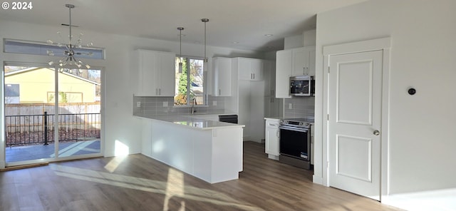 kitchen with white cabinets, a healthy amount of sunlight, kitchen peninsula, and appliances with stainless steel finishes