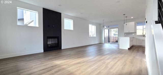 unfurnished living room featuring a fireplace, an inviting chandelier, and light hardwood / wood-style flooring