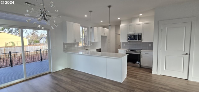 kitchen with kitchen peninsula, appliances with stainless steel finishes, backsplash, white cabinets, and dark hardwood / wood-style floors