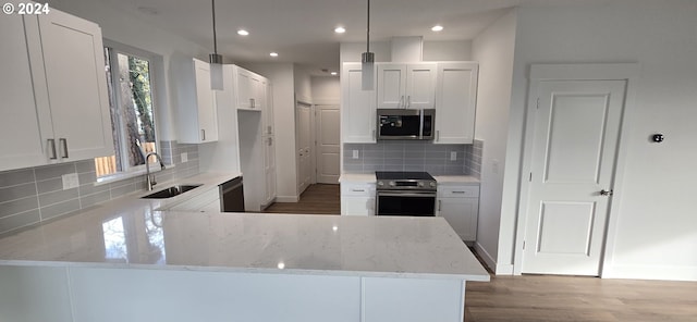 kitchen with kitchen peninsula, white cabinetry, sink, and appliances with stainless steel finishes