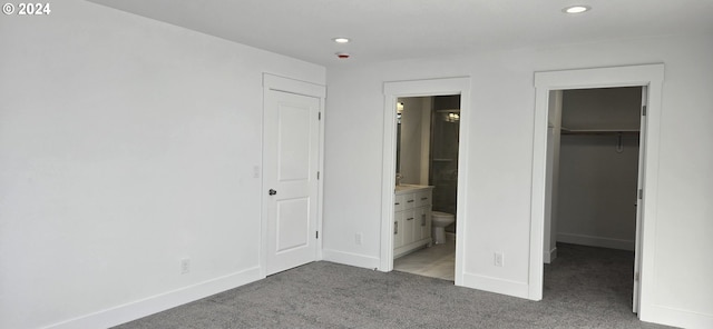 unfurnished bedroom featuring carpet flooring, a closet, a spacious closet, and ensuite bath