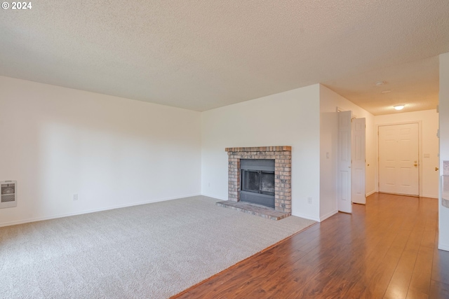 unfurnished living room with a textured ceiling, dark hardwood / wood-style floors, and a brick fireplace