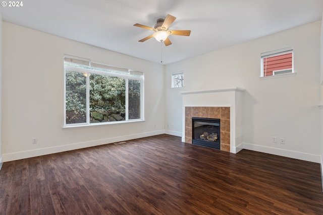 unfurnished living room featuring ceiling fan, dark wood-type flooring, and a tiled fireplace