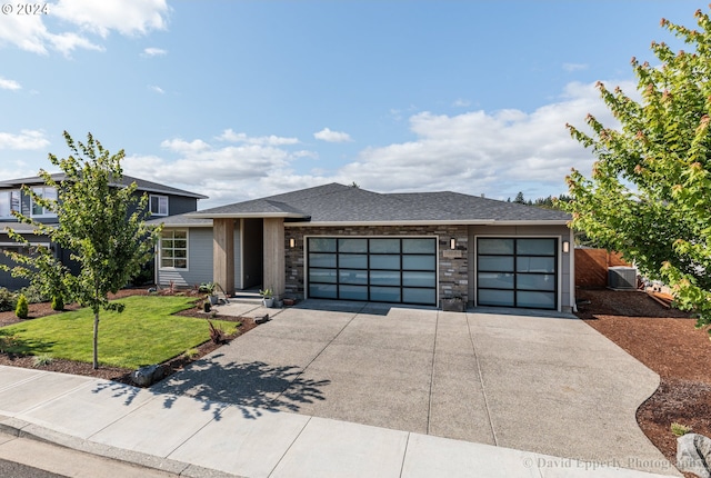 prairie-style home with a garage, a front yard, and central AC unit