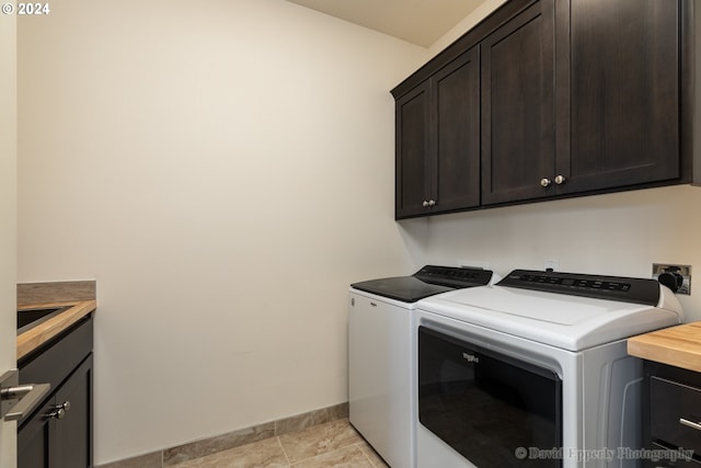 laundry room with cabinets, washing machine and dryer, and light tile patterned floors