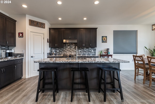 kitchen featuring dark brown cabinets, a kitchen island with sink, and light hardwood / wood-style flooring