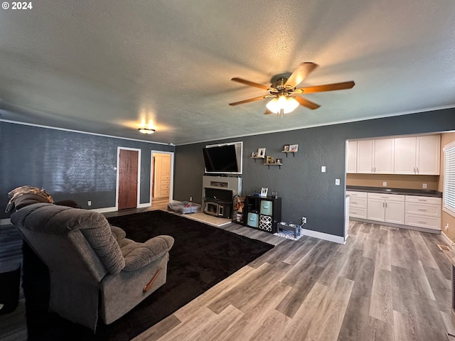 living room featuring ceiling fan, light hardwood / wood-style floors, and a textured ceiling