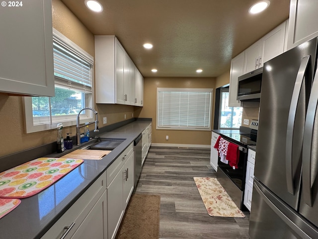 kitchen featuring appliances with stainless steel finishes, dark hardwood / wood-style flooring, a textured ceiling, sink, and white cabinetry