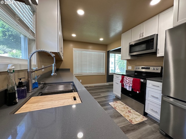 kitchen featuring sink, dark hardwood / wood-style flooring, a textured ceiling, white cabinets, and appliances with stainless steel finishes