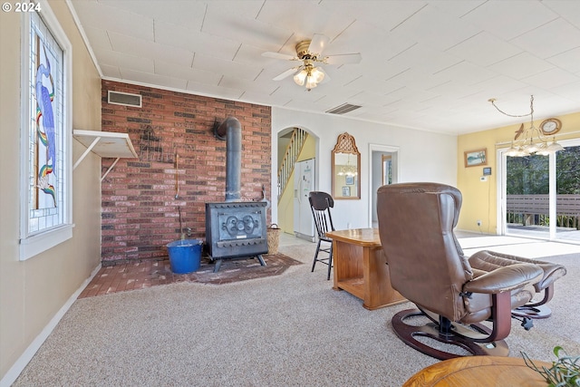 carpeted office space featuring brick wall, a wood stove, and ceiling fan