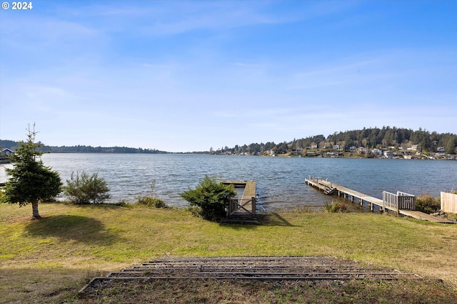 view of dock with a water view and a lawn