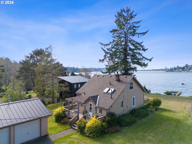 exterior space with a yard, a deck with water view, and an outdoor structure