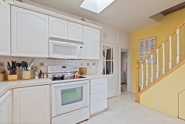 3770 NE 12th St, Otis, OR 97368 - kitchen featuring decorative backsplash, white cabinetry, a skylight, and white appliances