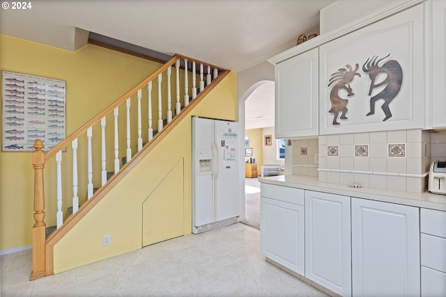 kitchen with decorative backsplash, white cabinets, light tile patterned flooring, and white refrigerator with ice dispenser