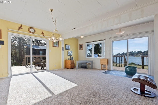 living room with carpet, ornamental molding, a chandelier, and a water view