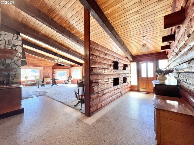 unfurnished living room featuring a stone fireplace, vaulted ceiling with beams, plenty of natural light, and wooden ceiling