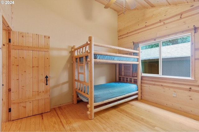 unfurnished bedroom featuring vaulted ceiling, hardwood / wood-style floors, and wooden walls