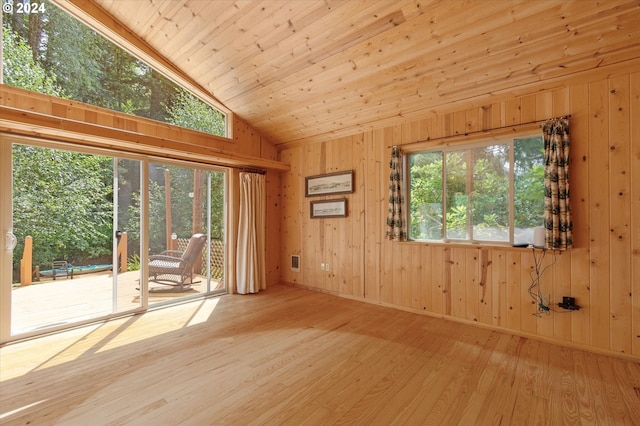 unfurnished room featuring vaulted ceiling, wooden walls, wood ceiling, and light hardwood / wood-style floors